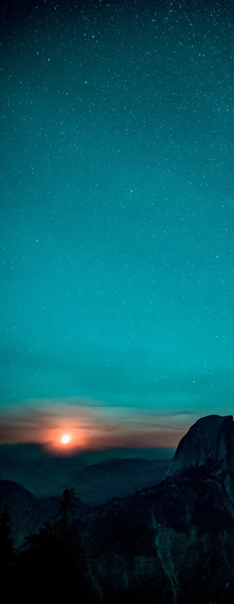 sunrising over mountains with stars in the sky